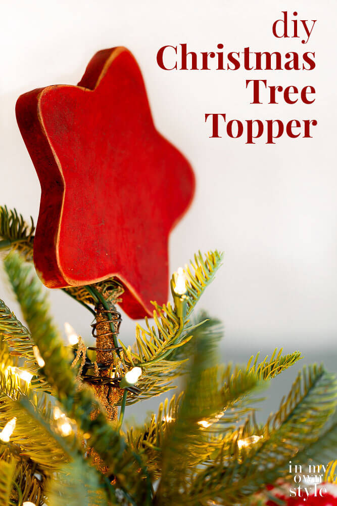 Rustic red wood star Christmas tree topper on tree. Text overlay on image says DIY Christmas tree topper.