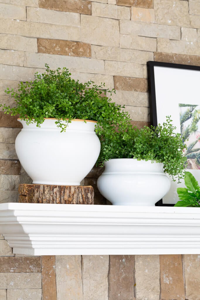 After Christmas Winter decorating ideas for mantels. White planters and greenery on stone and white fireplace.