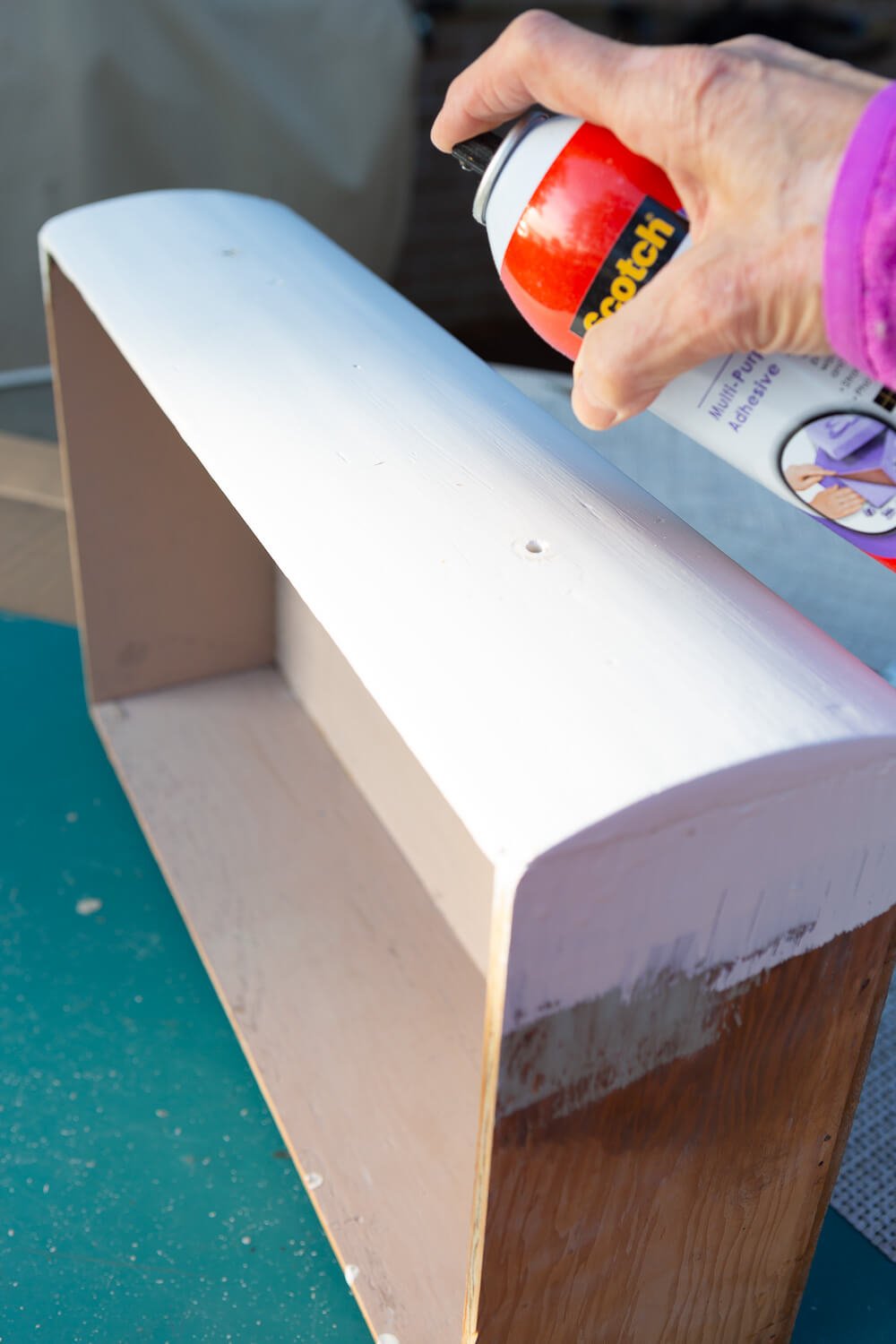 applying spray adhesive to the front of a drawer for a woven front furniture makeover