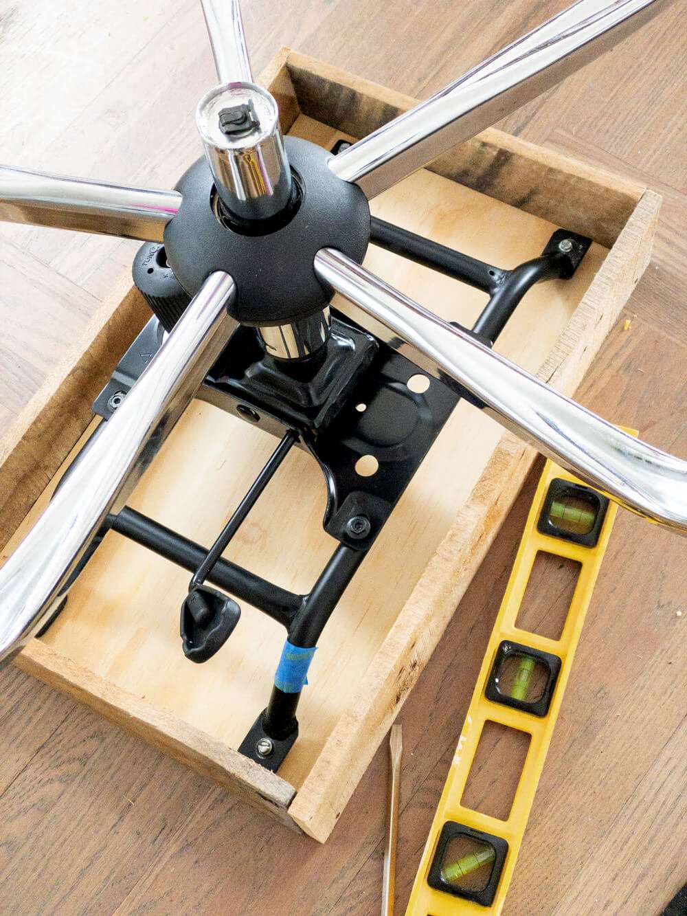 Attaching the base of an office chair to a wood box to make to hold a file folder organizer.