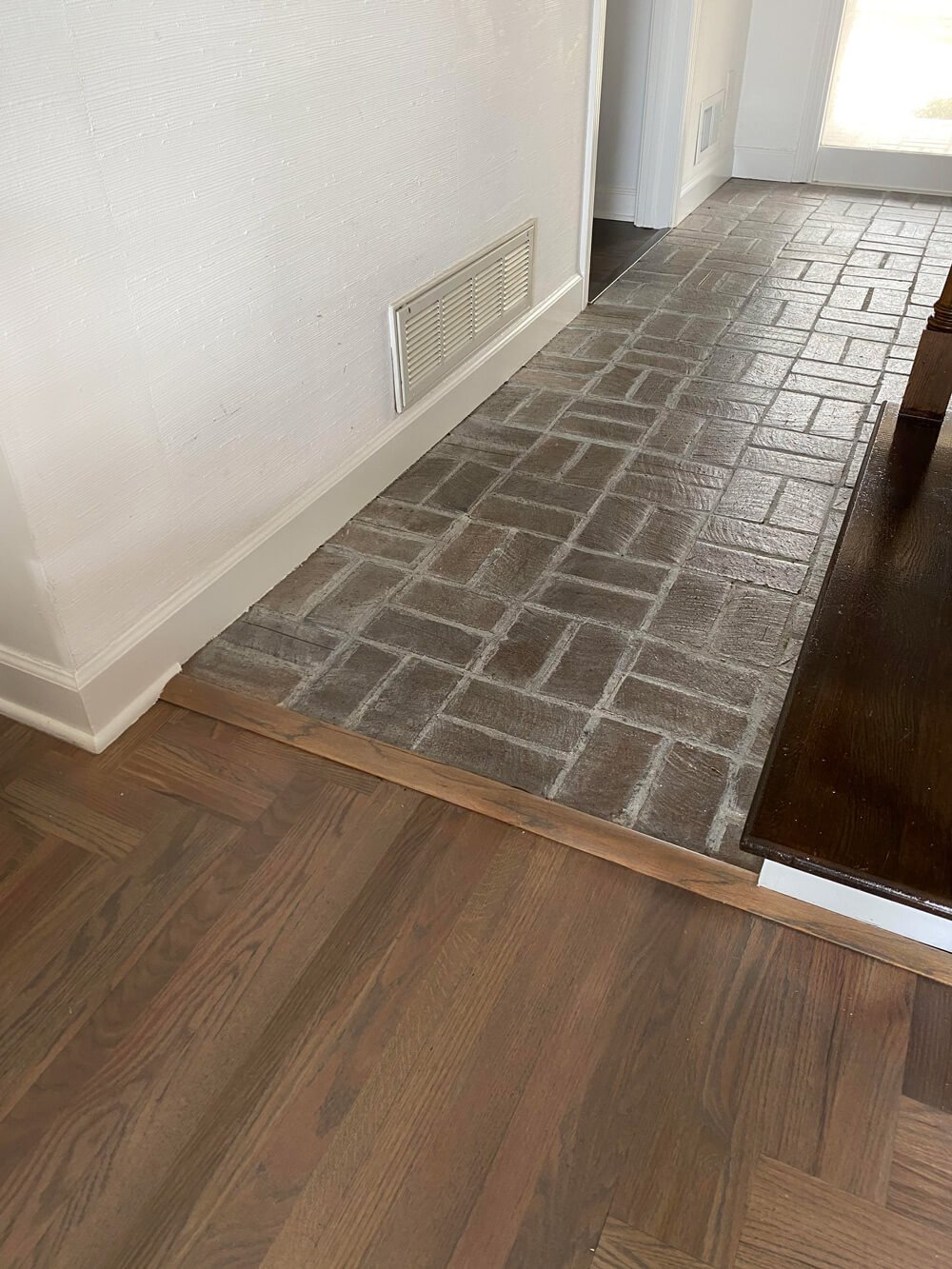 flooring transitions from living room to brick floor in foyer