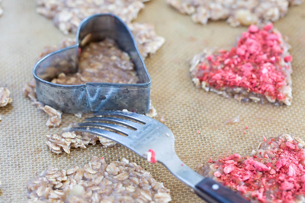 Using a heart shaped cookie cutter to make healthy Valentine's Day cookies.