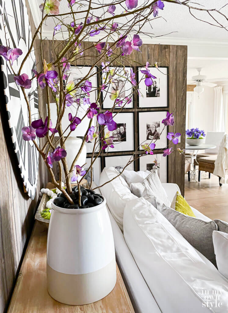 Faux blooming branches in large planter behind a sofa