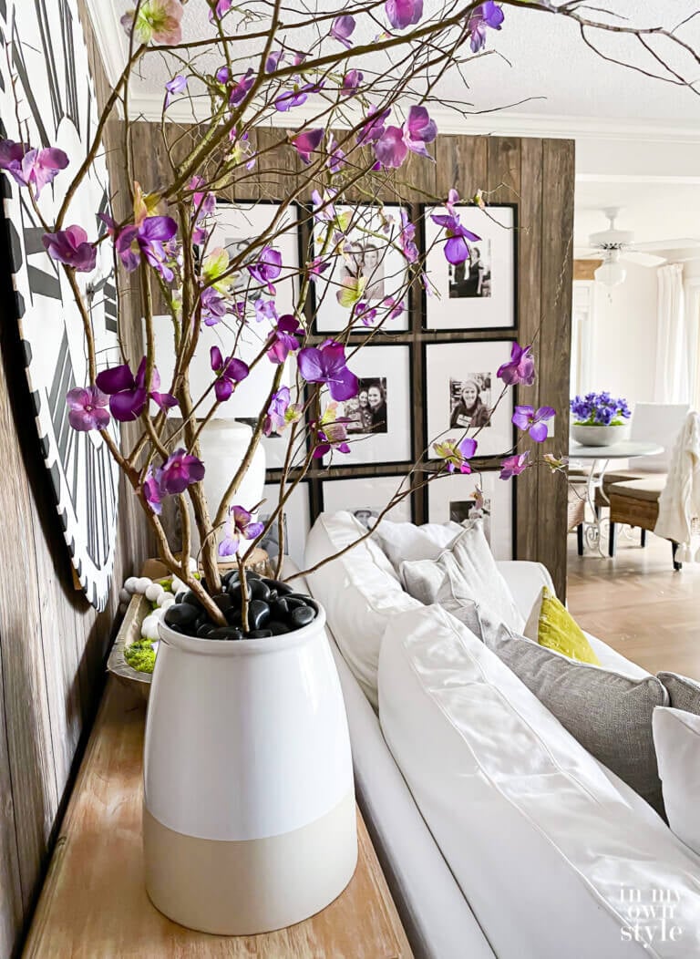 Faux blooming branches in large planter behind a sofa