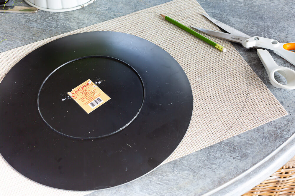Showing how to trace around a large plate on a rectangular placemat to make a round placemat.