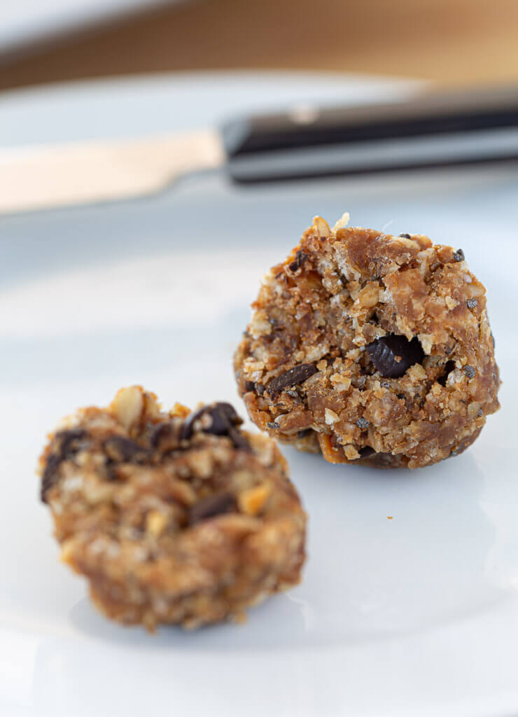 no bake protein ball cut in half on white plate.