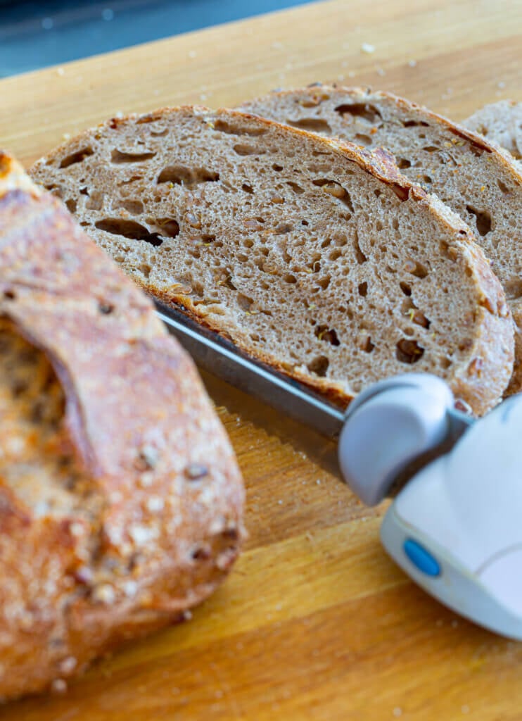 Sourdough bread being cut on a wood cutting board. Yes bread can be part of a plant-based weight loss success story.