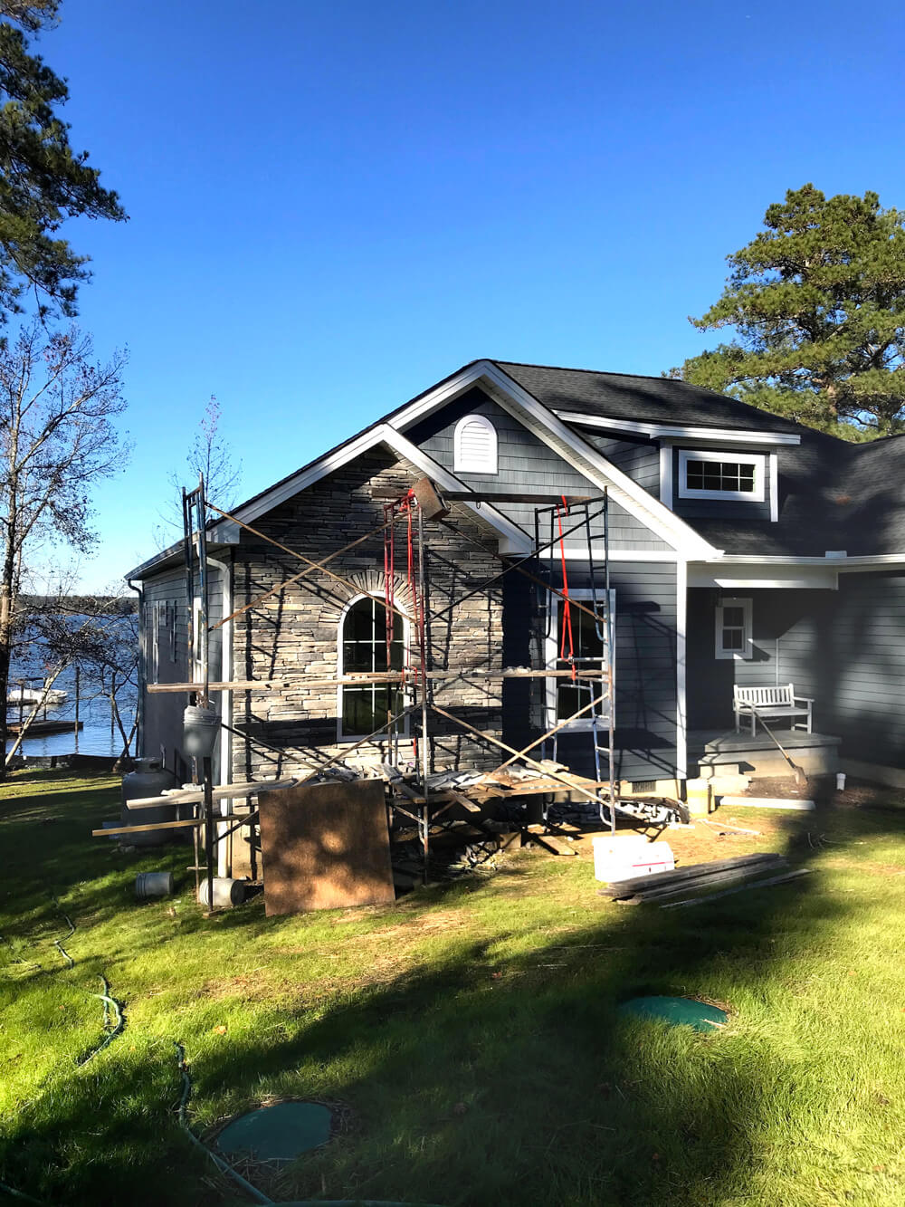 Front exterior of house being built on shores of a lake.