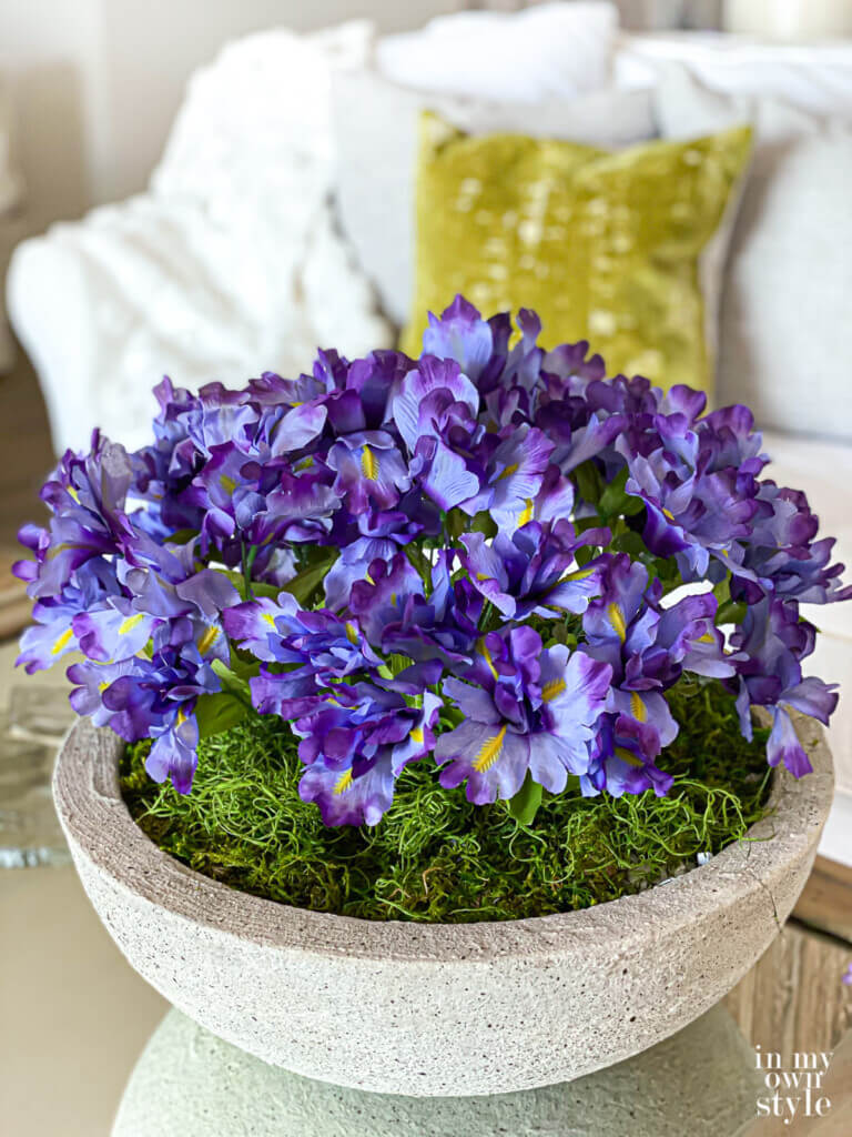 Cut flowers in a low bowl planter on a coffee table.