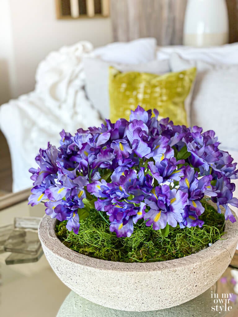 Cut flowers in a low bowl planter on a coffee table.