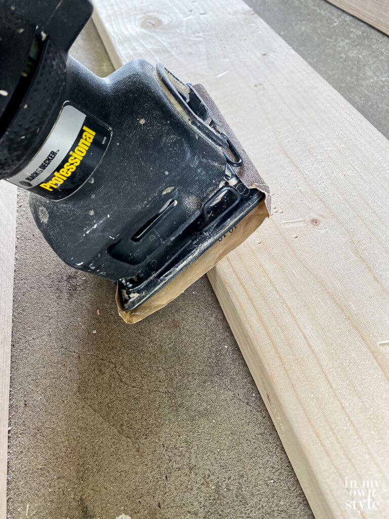 Sanding edge of each pine board before assembling table.
