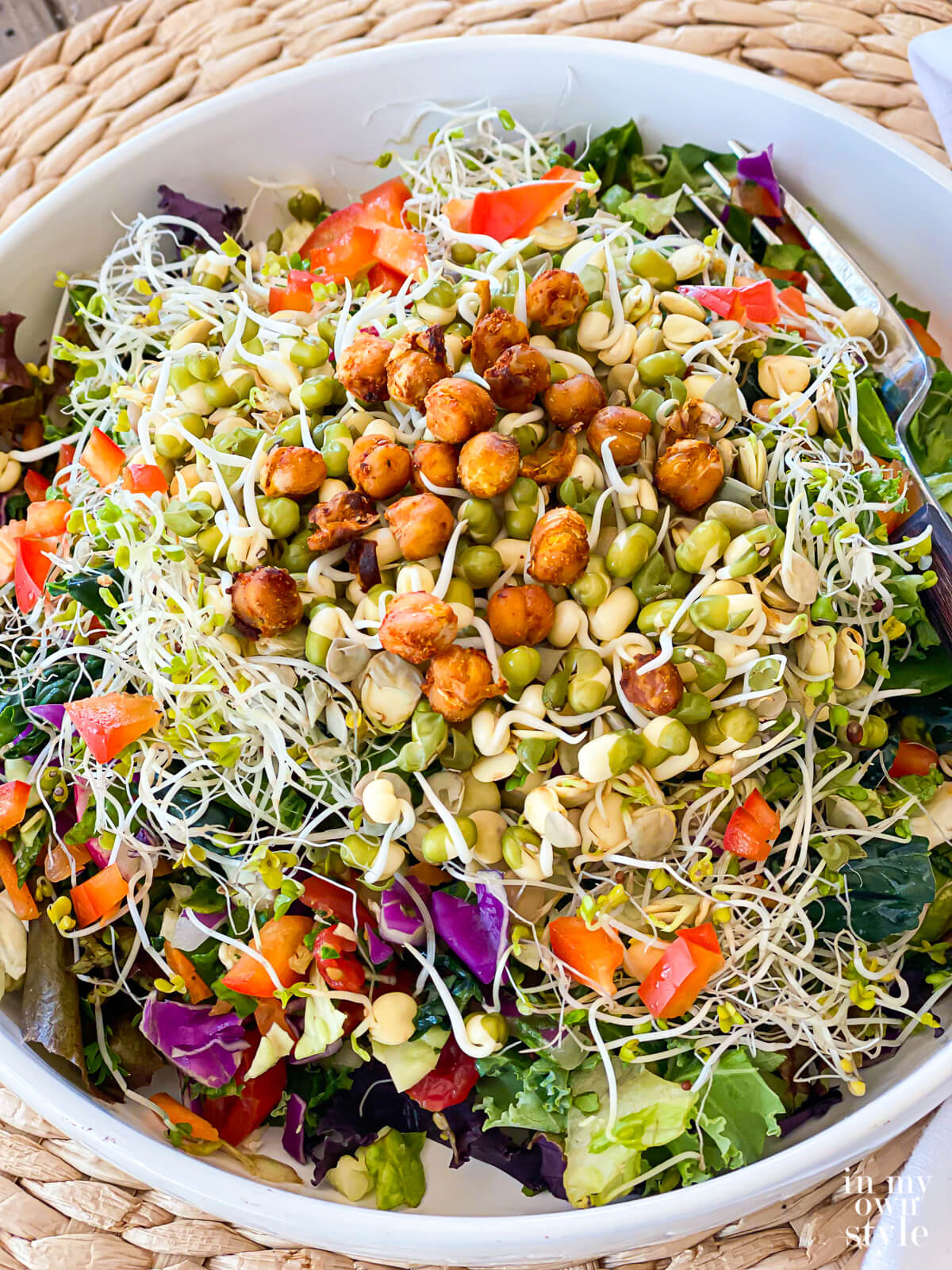 Close up shot of a chopped salad with roasted chickpeas, sprouted mung beans, lentils and broccoli sprouts on top.