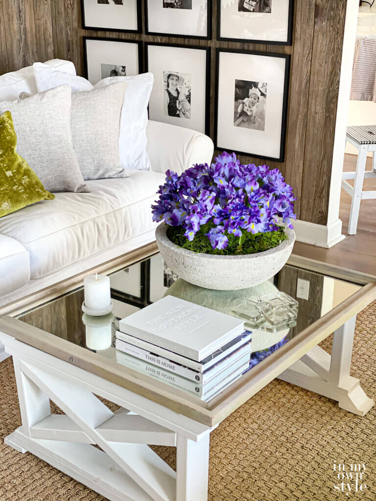 Looking down on coffee table with a low bowl planter on it that is filled with moss and purple flowers.