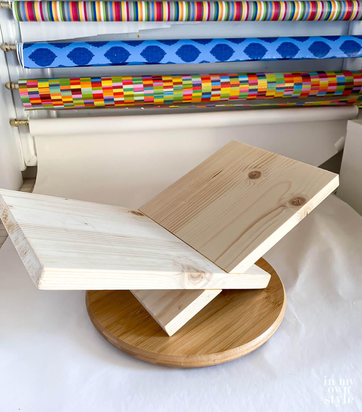 Unfinished x shaped book holder on top of wood turntable.