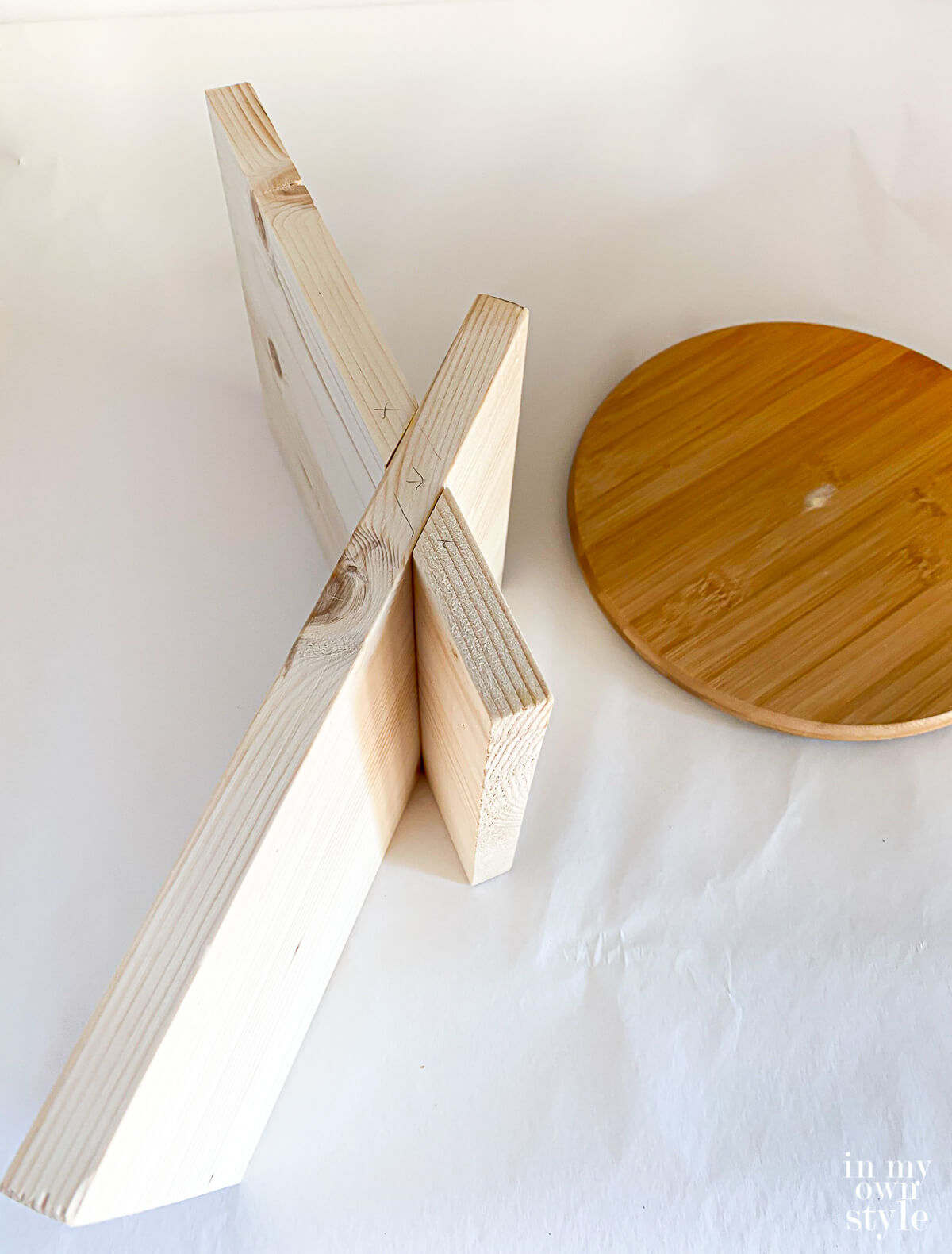 unpainted x shape book stand after being assembled. Shown on its side to see how to put together.