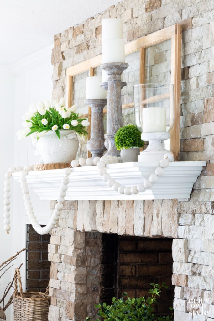 Side view of stone fireplace decorated for summer using a green and white as the color scheme.