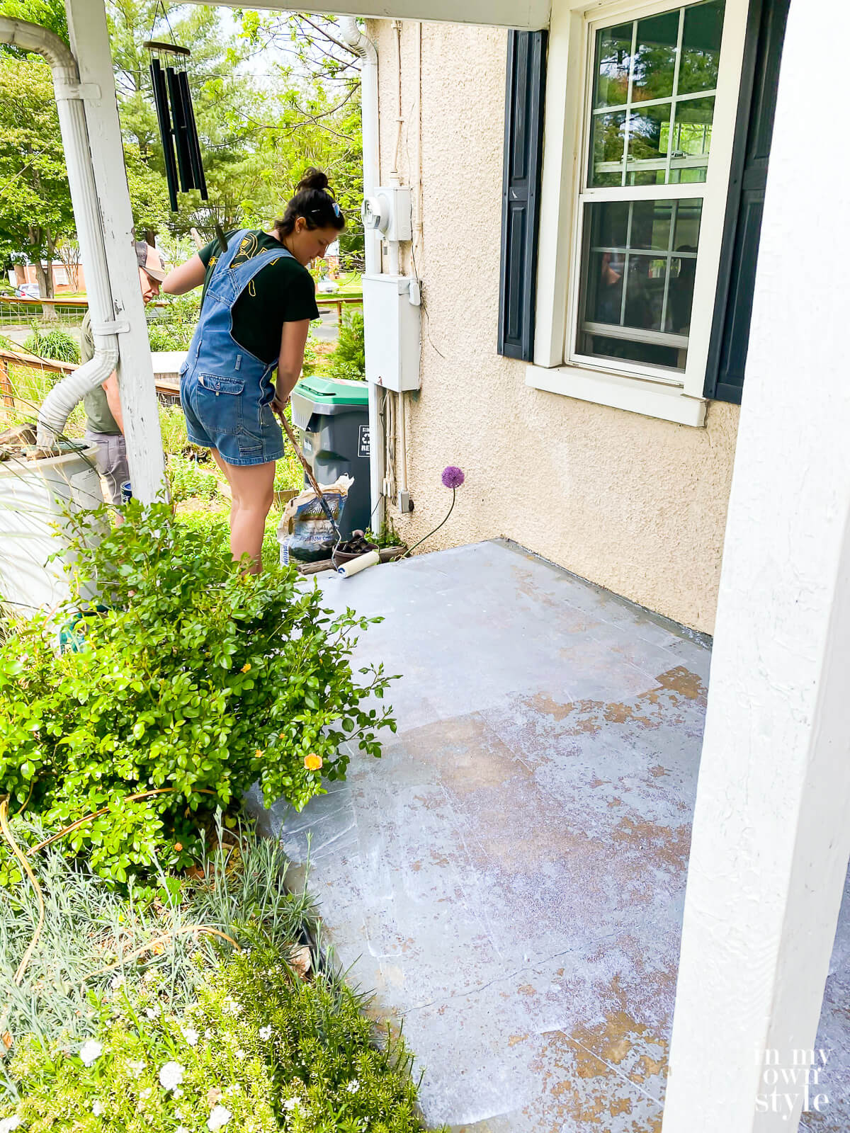 Rolling on concrete primer on porch floor.