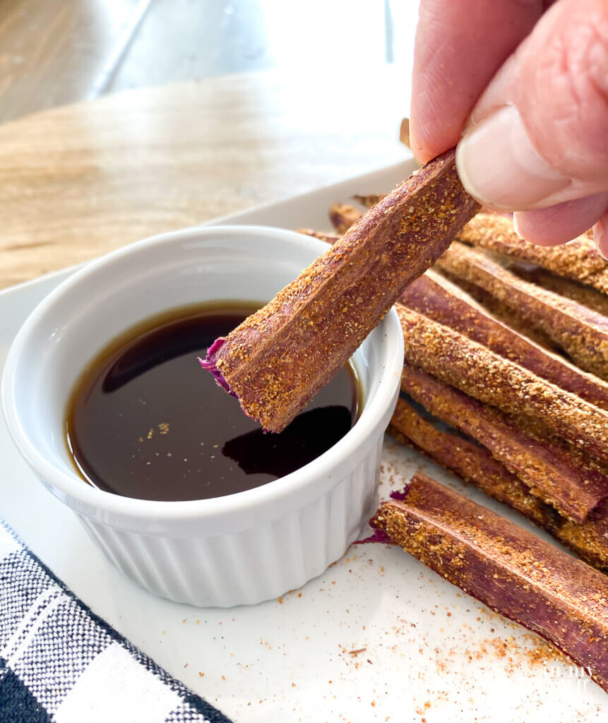 Dipping a baked purple sweet potato fry into malt vinegar.