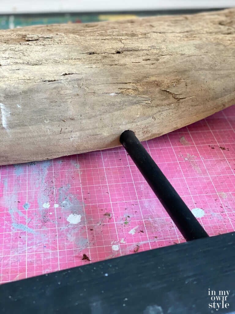 Attaching dowels to piece of driftwood and a black painted stand.