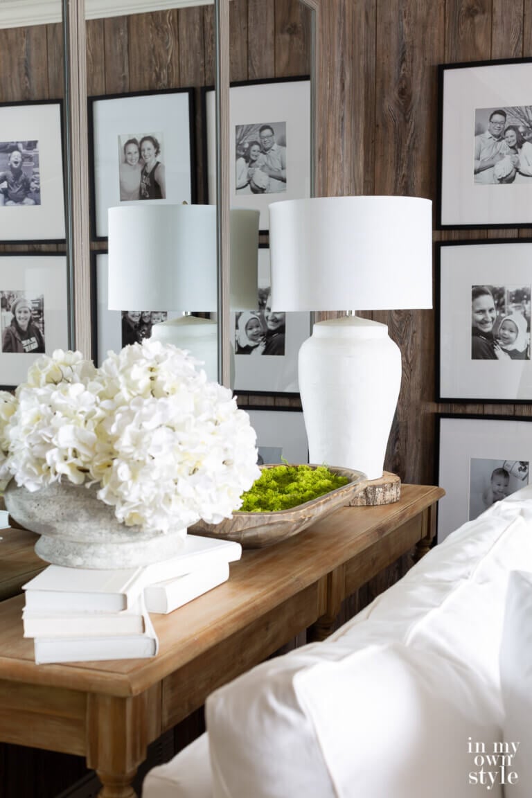 Console table with a trio of large wall mirrors behind it. The table is decorated with white and green.