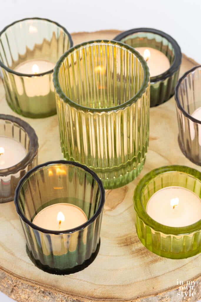 Above view shot of rustic wood slice candle holder with green glass ribbed votive holders.