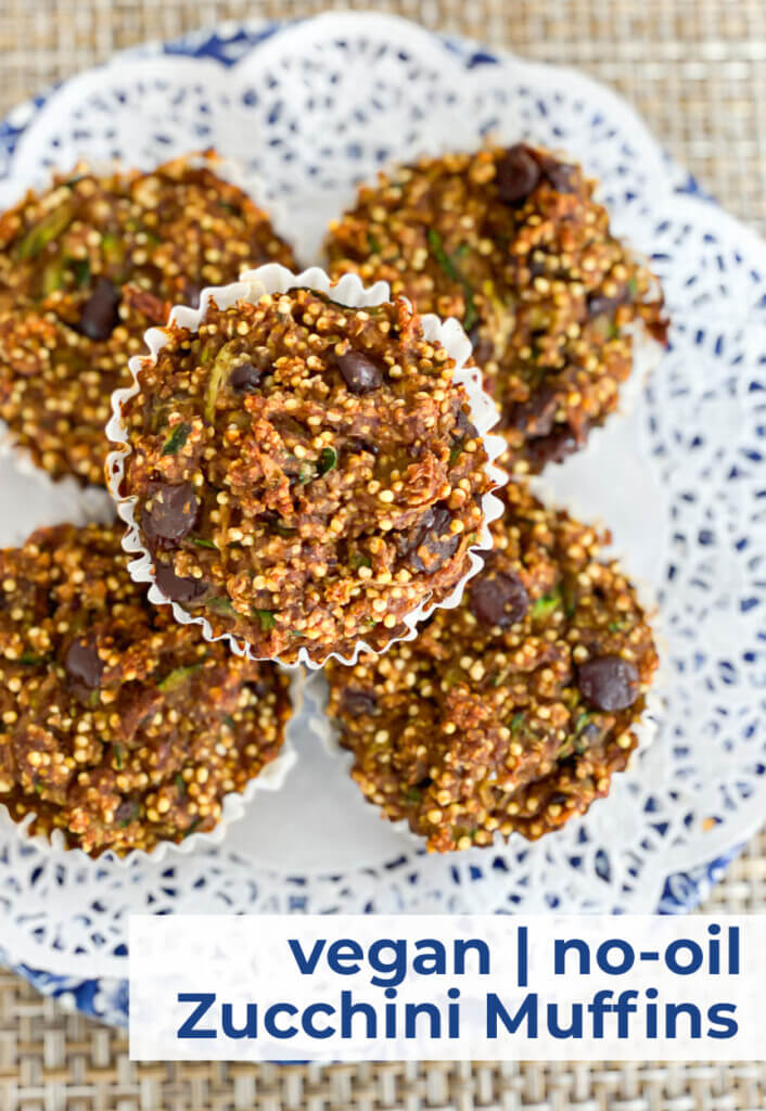 Vegan no-oil zucchini muffins stacked on a doily covered blue and white plate.