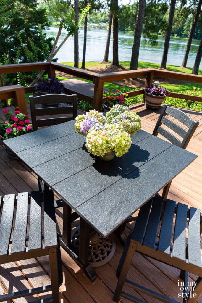 Birds eye view of a POLYWOOD La Casa Cafe Farmhouse Trestle Bar set in black on a backyard deck.