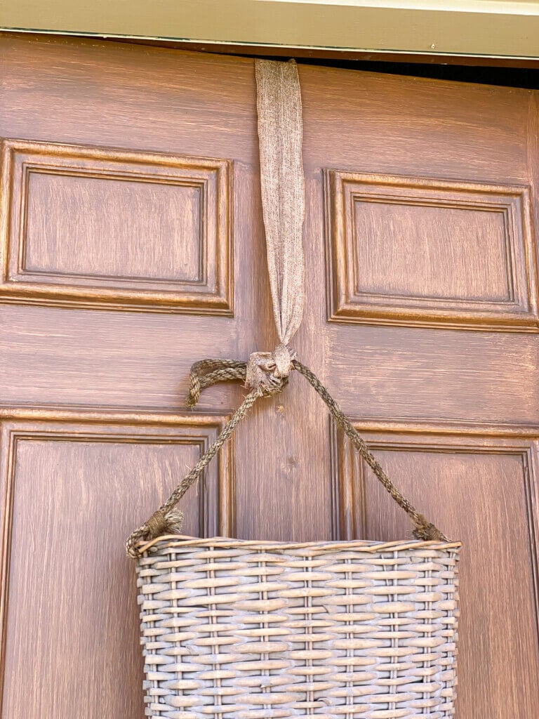 flat sided hanging basket on exterior door hung with ribbon.
