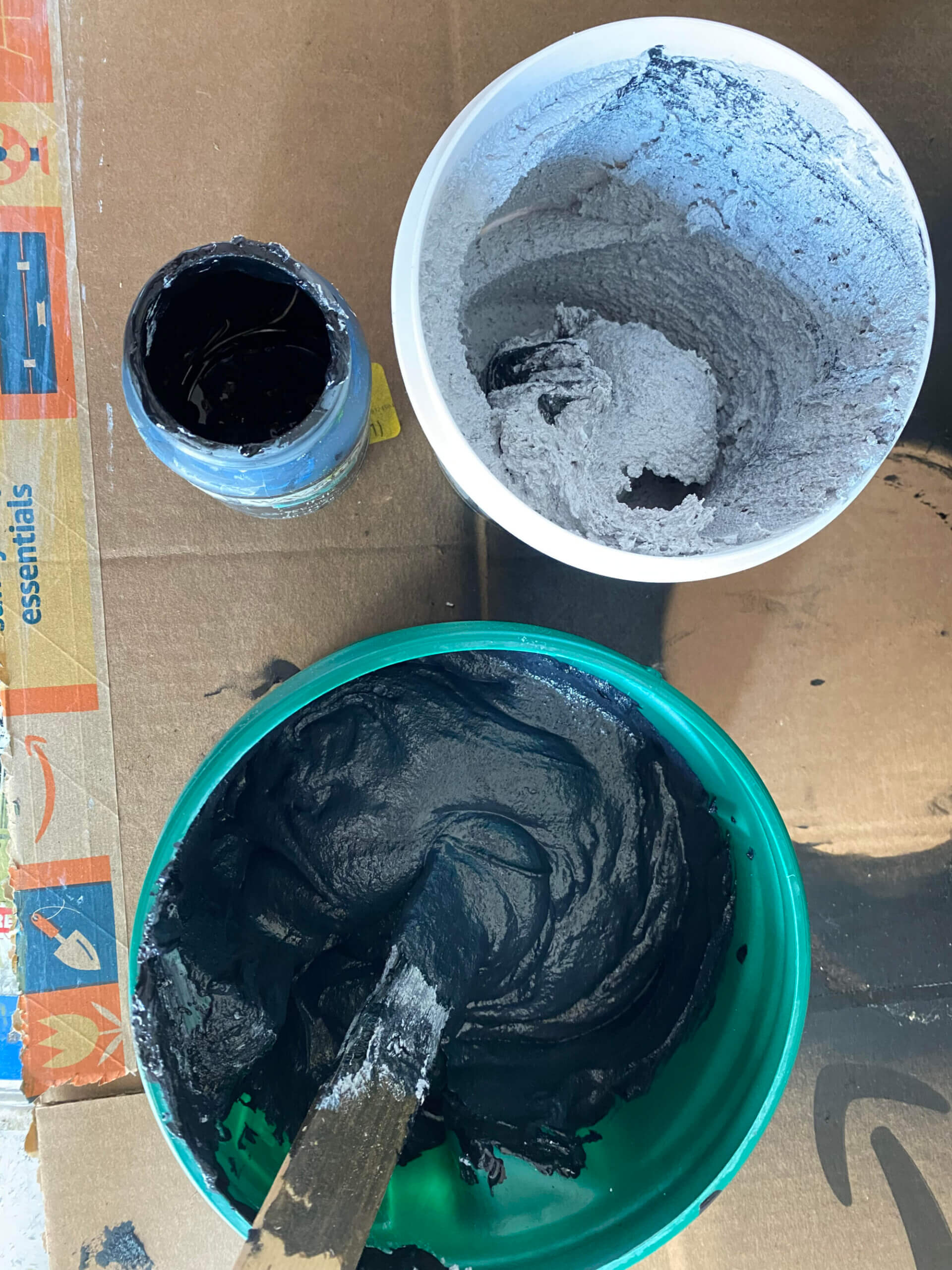 Mixing black chalk paint and concrete patch in two plastic containers.