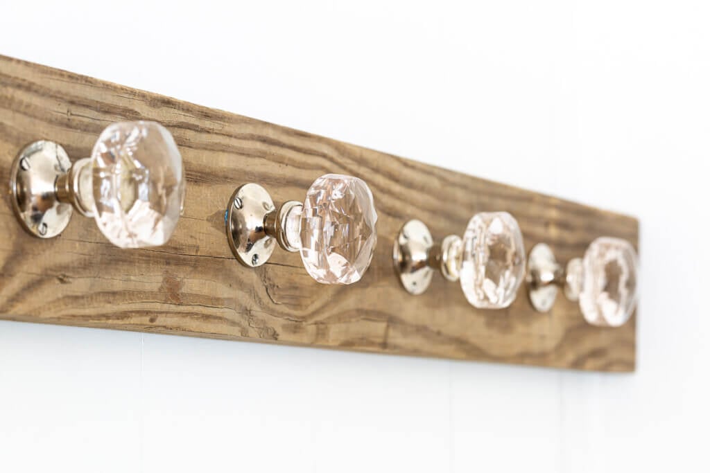 Wood board and glass doorknobs turned into a blanket holder for living room.
