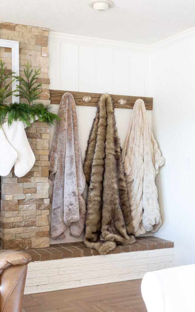 3 fur throw blankets hung on a wall mounted blanket holder.