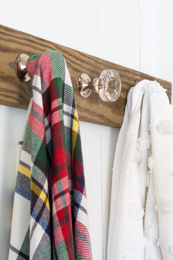 blanket display ideas - wood holder on wall using doorknobs as hooks.