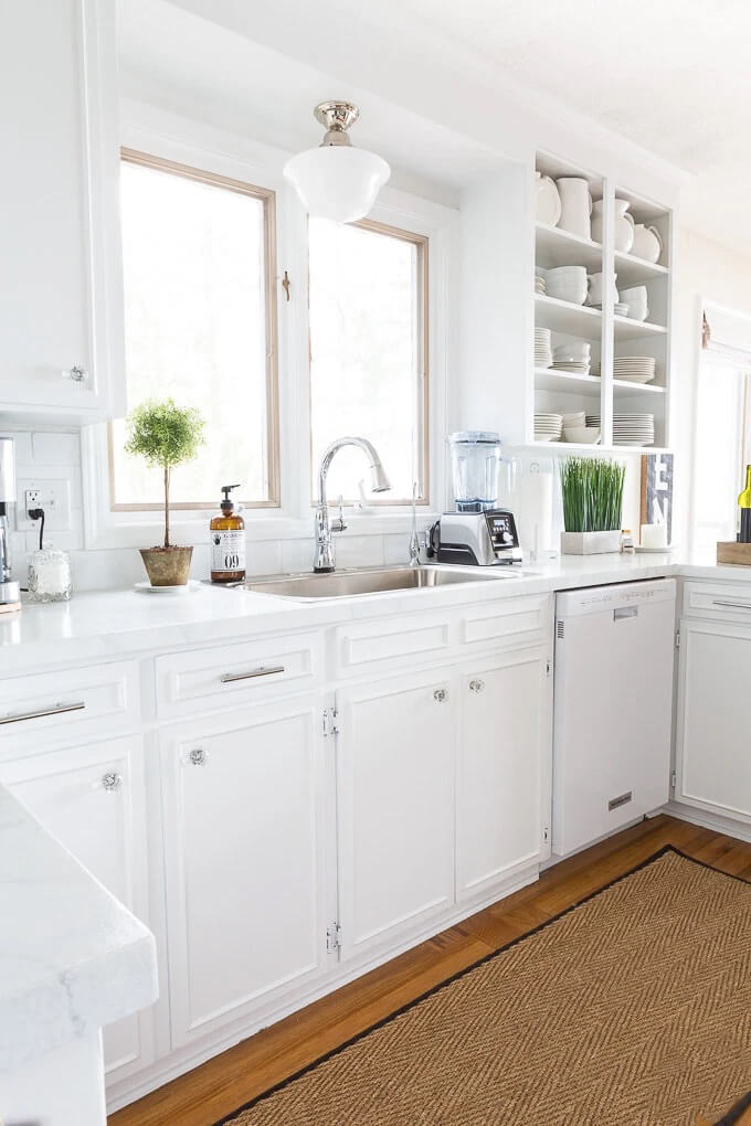 Removing Kitchen Cabinet Doors to Create Open Shelving in a white kitchen where the brown counters were painted to look like Carrara marble.