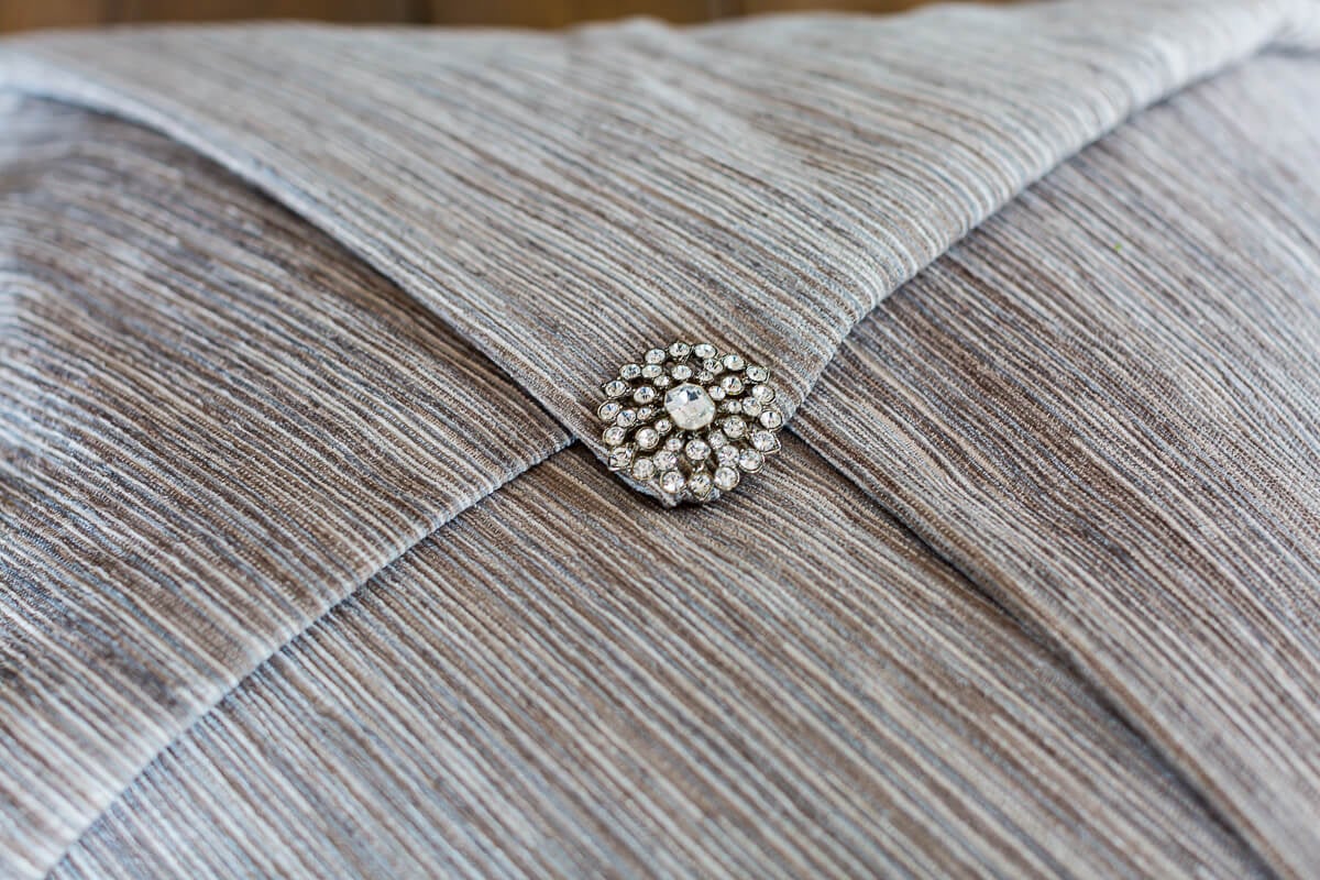 Rhinestone pin that secures a decorative throw pillow on a pillow.