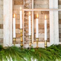 Christmas decorated mantel with empty vintage frames and brass candlesticks.