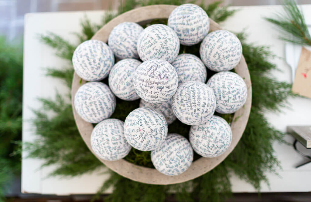 Looking down into large bowl filled with ball ornaments covered in script paper.