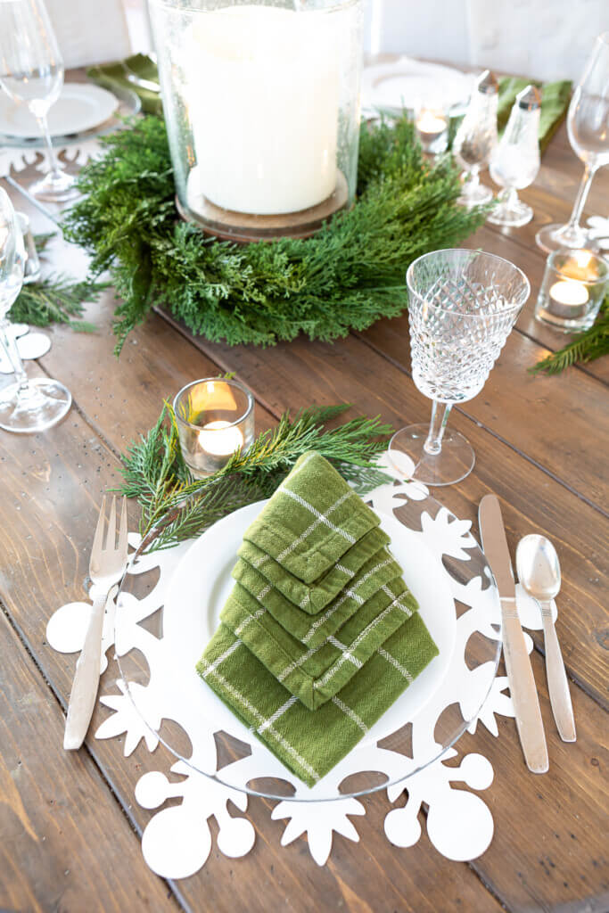 Holiday table setting snowflake placemat and clear glass plates.