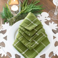 Folded green napkin into a Christmas tree shape on a dinner plate