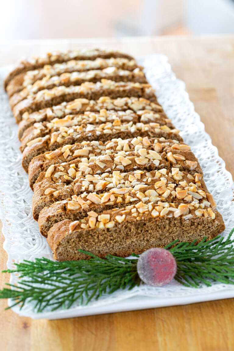 Vegan biscotti cut into slices on a plate with Christmas greenery on it.