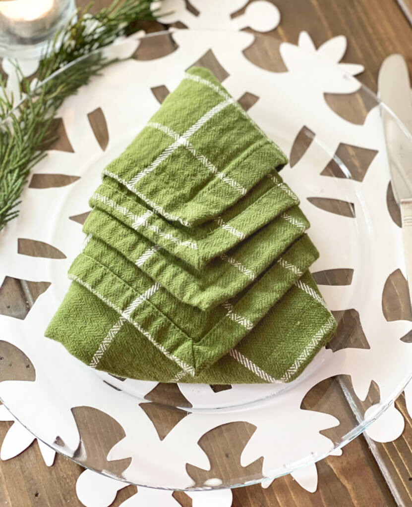 A green and white napkin folded in a Christmas tree shape.