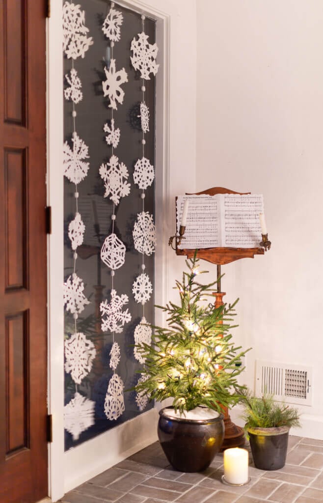 Snowflake window decor. 3 rows of Paper snowflakes hung in a tall window for winter decor.