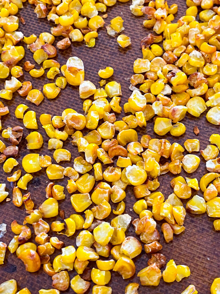 close up of roasted corn kernels on a baking sheet.