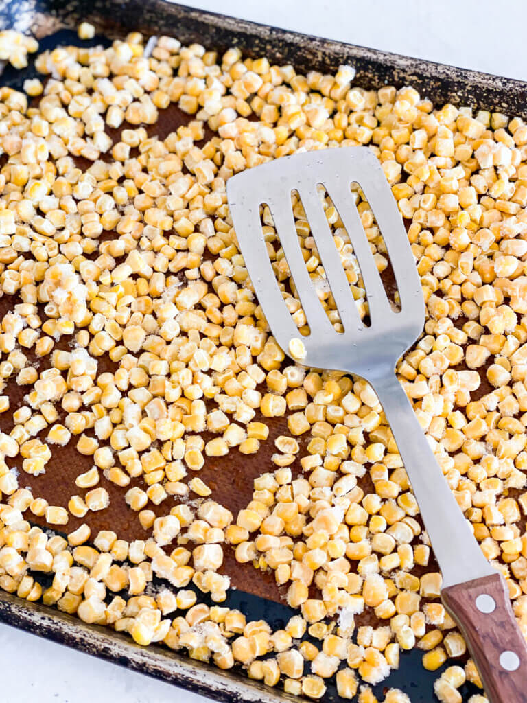 frozen corn kernels being prepared for roasted in an oven.
