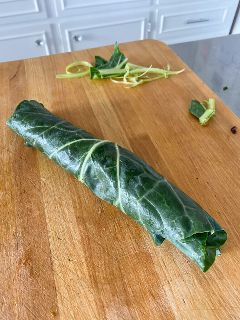 A collard green wrap on a cutting board