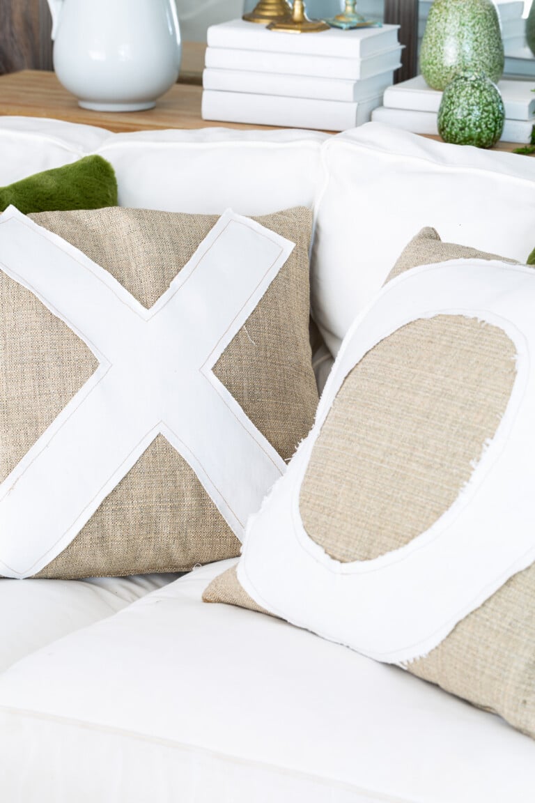X and O throw pillows on a white sofa.