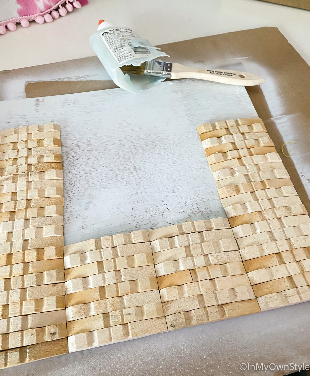 Gluing wood clothespins on plywood to make a frame.