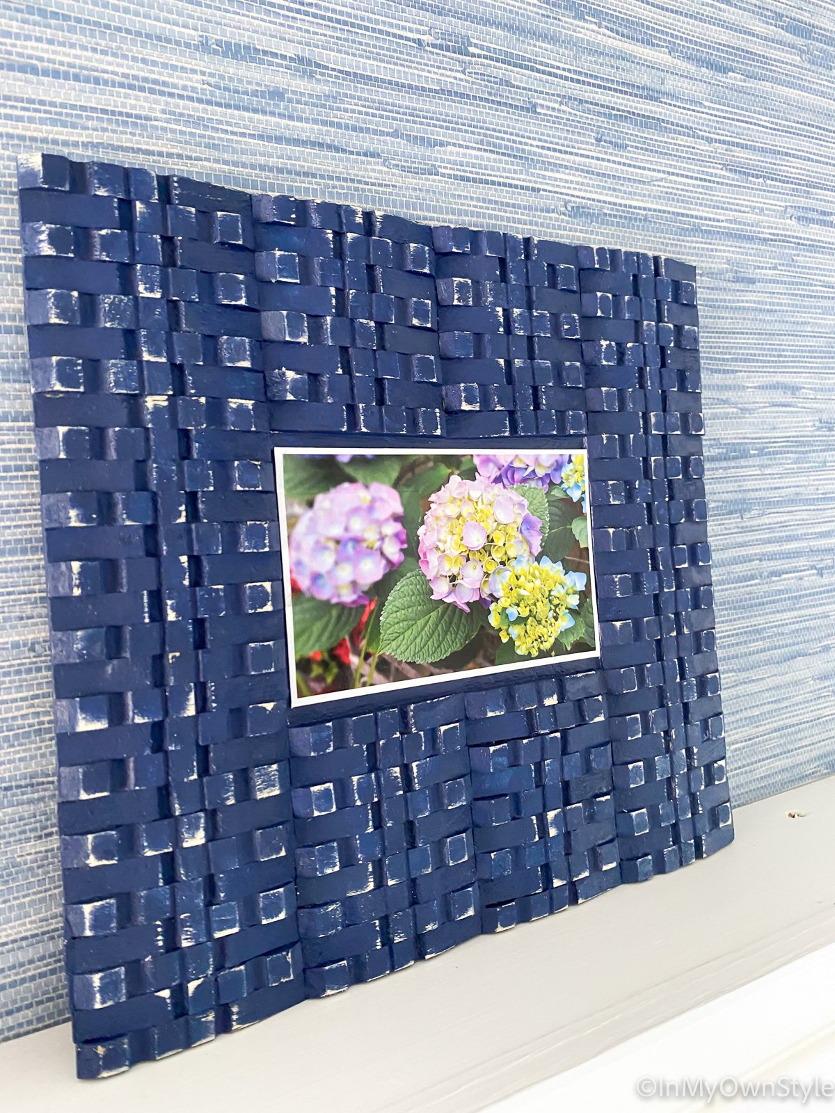DIY picture frame with clothespins leaning against a wall on a ledge.