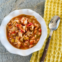 A bowl full of Ikarian stew with a napkin and spoon on the side.