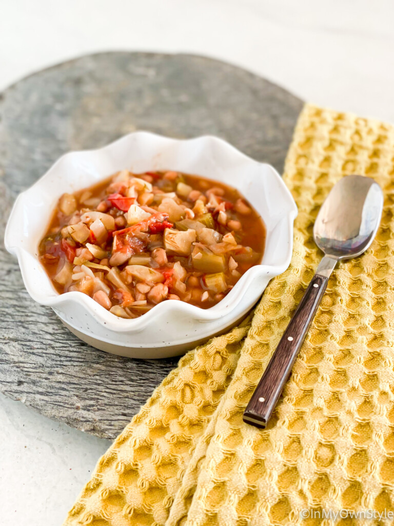 longevity stew in a bowl with a cloth napkin and spoon on the side