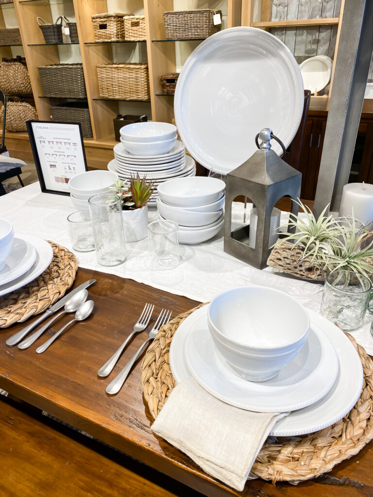White table place settings in wood table in Pottery Barn store.